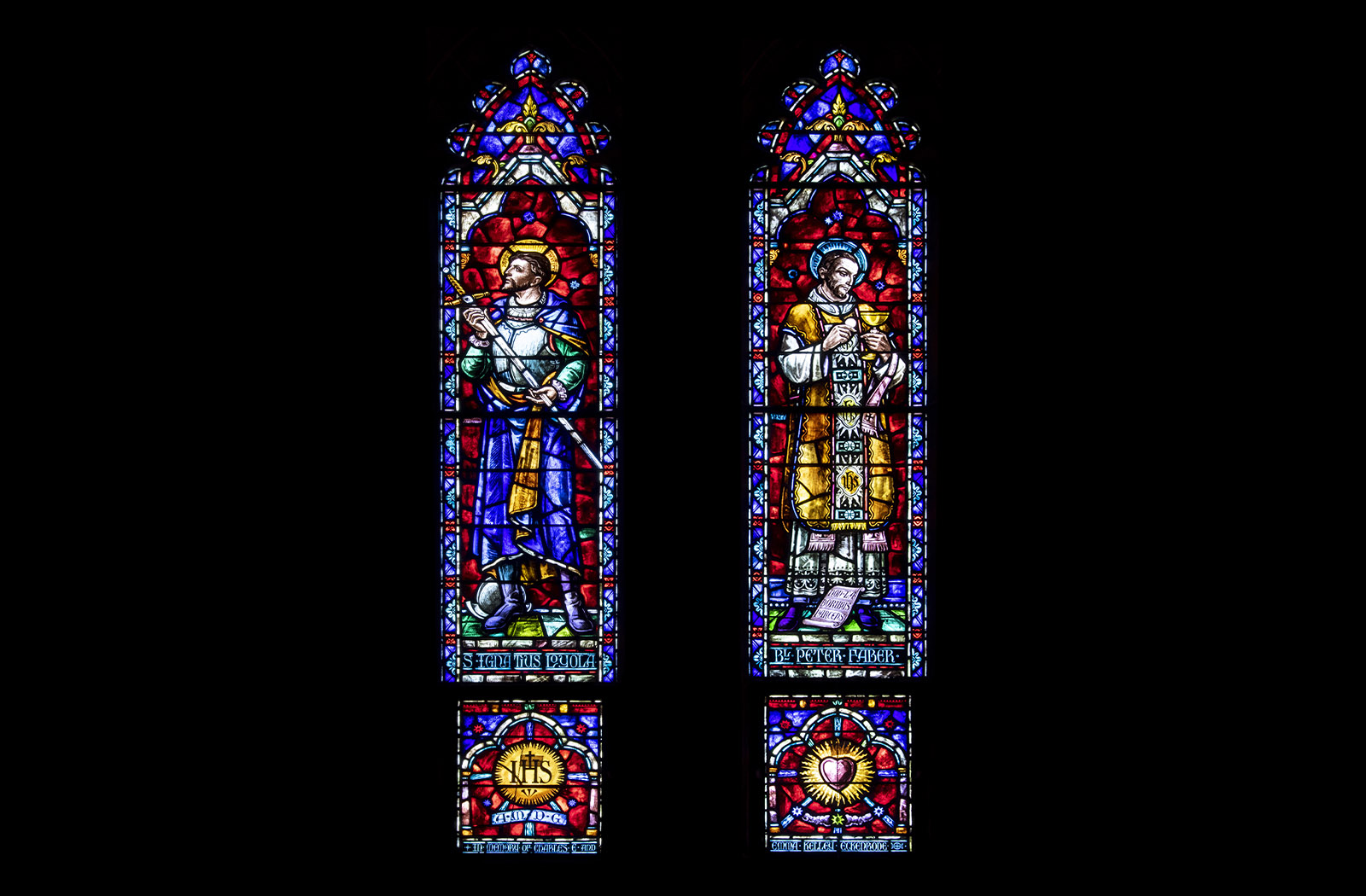 Two colorful stained glass panels of St. Ignatius Loyola and St. Peter Faber