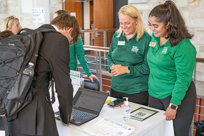 Two Career Center staff members smiling at a career fair registration table