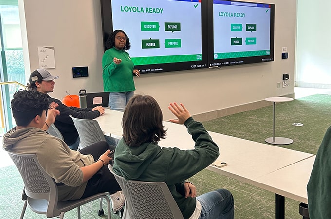 A career center staff member teaches in front of a large display while a student raises their hand