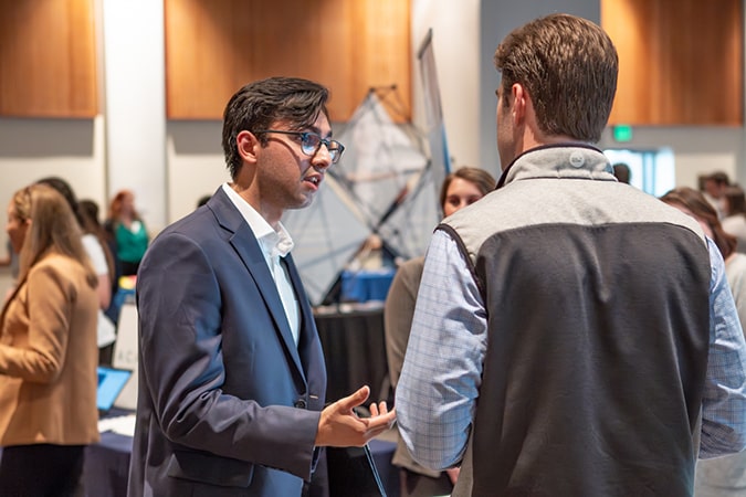 A student in a suit in conversation with a company representative