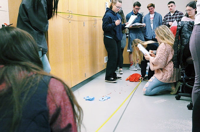 Forensics class gathers around to analyze a mock crime scene.