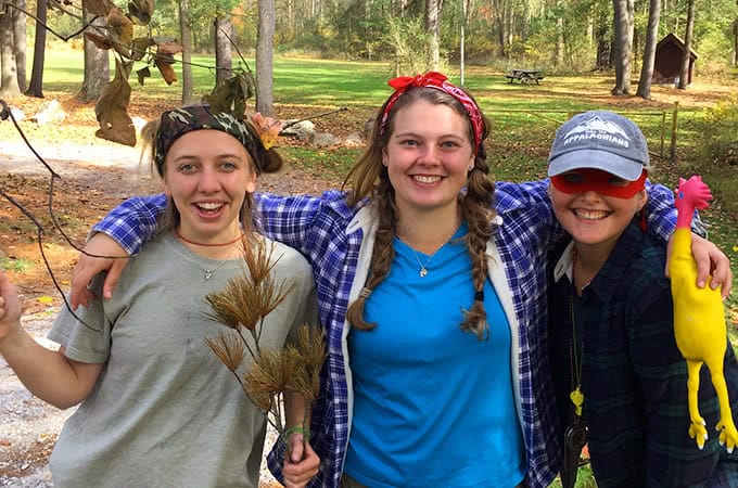 Three students in the woods smiling for the camera