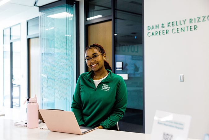A student smiles at the reception desk of the Rizzo Career Center