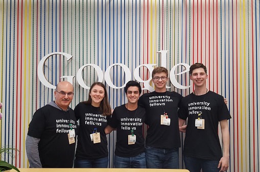 Group of students posing in front of a wall with the Google logo