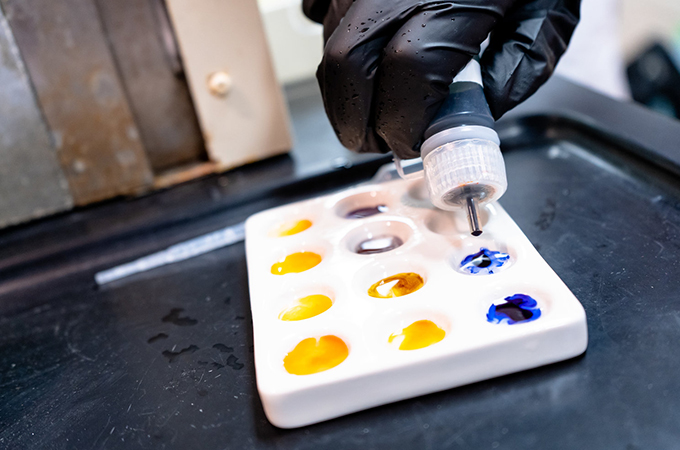 Student drops a chemical solution into a tray.