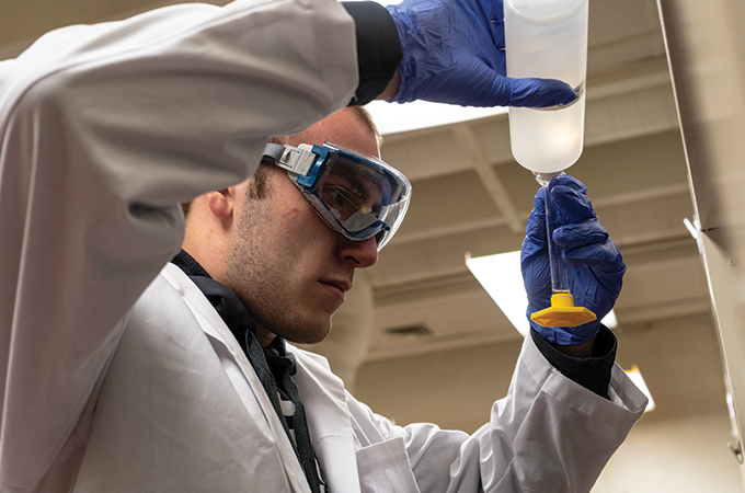 A student pours solution into a beaker.