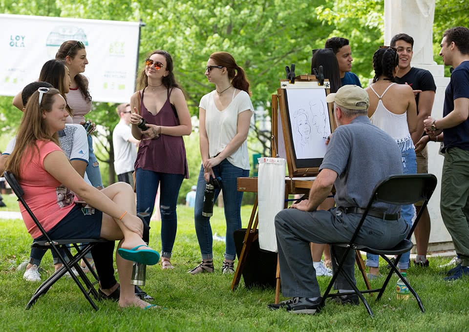 An artist drawing a caricature of a student while others wait in line