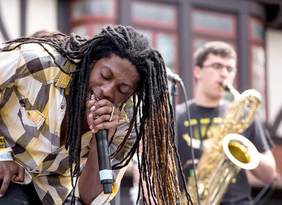 A singer on stage, with a saxophonist playing in the background