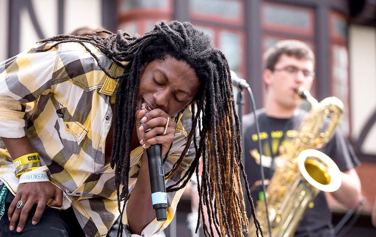 A singer on stage, with a saxophonist playing in the background