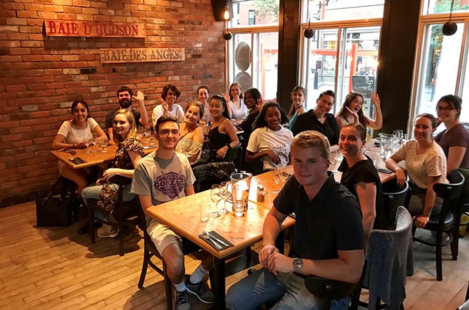 Group of Loyola students waving to the camera during a meal in Montreal