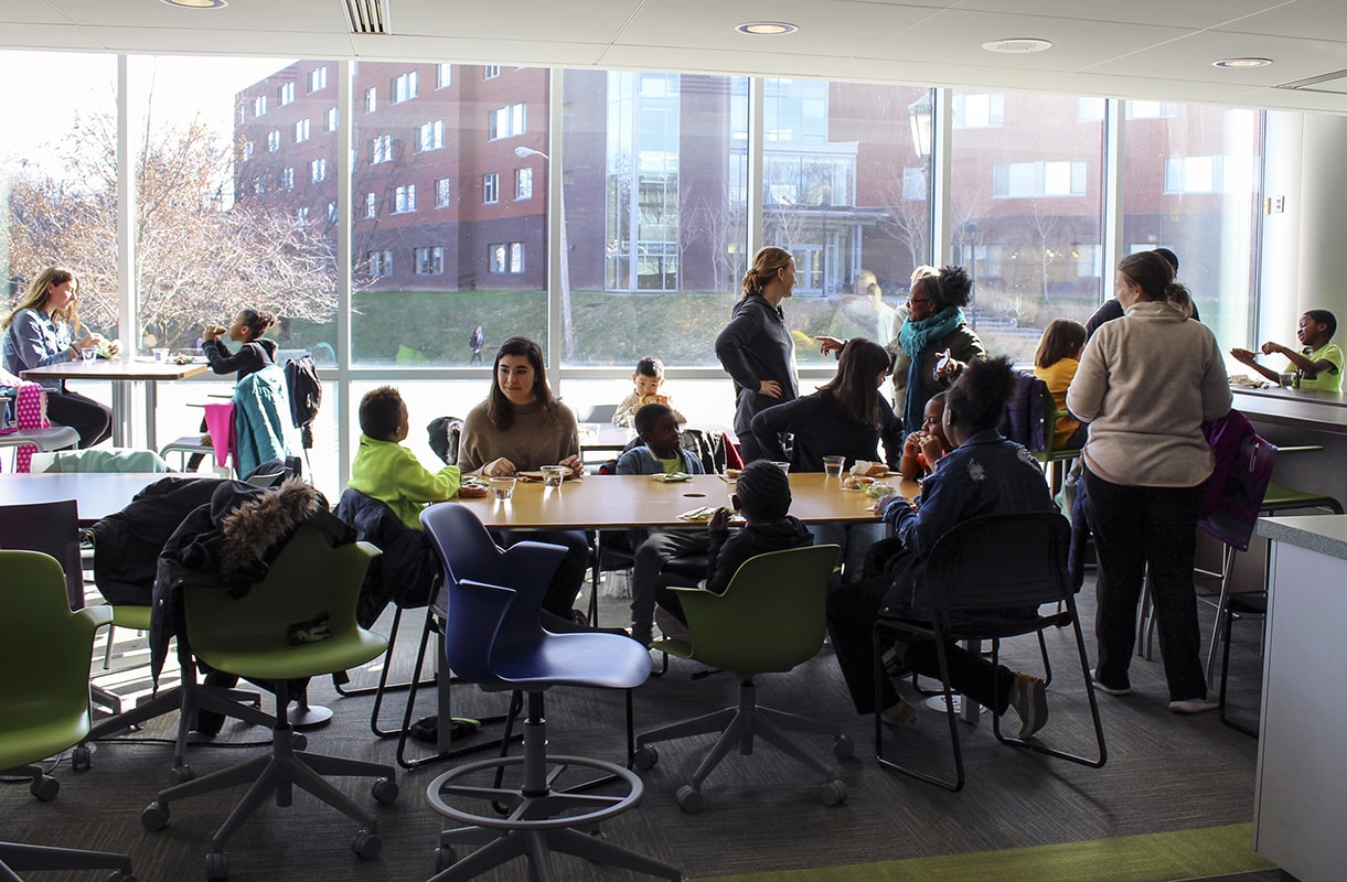 Loyola students and local elementary students sitting around a table in the Loyola Notre Dame library