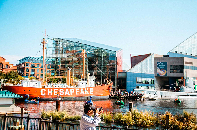 A large red boat and dragon paddle-boats can be seen in the harbor in front of the National Aquarium