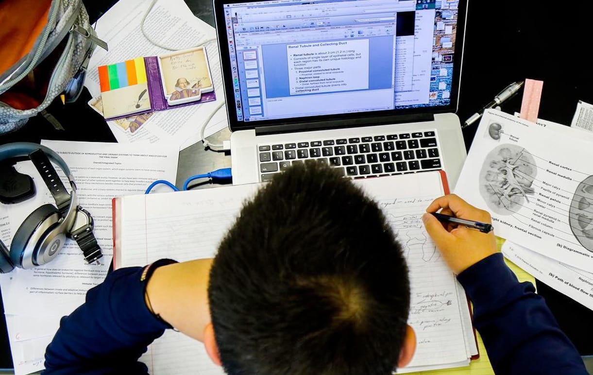 An overhead view of a student studying with a notebook, laptop, and other notes