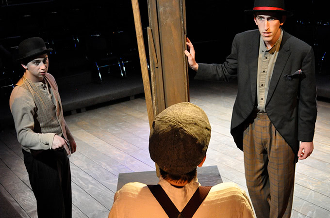 Three students wearing old-fashioned clothes and talking on stage