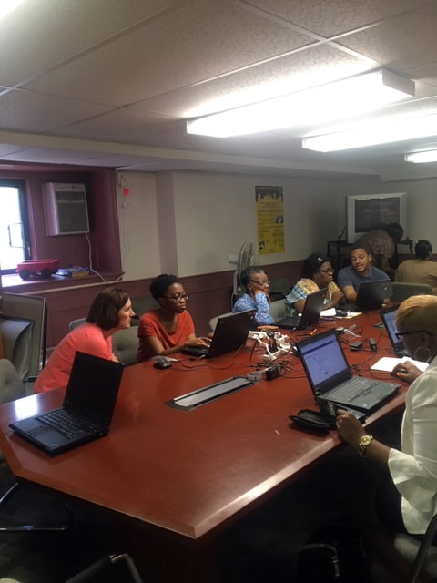 Group of people sitting at a large conference table using laptops