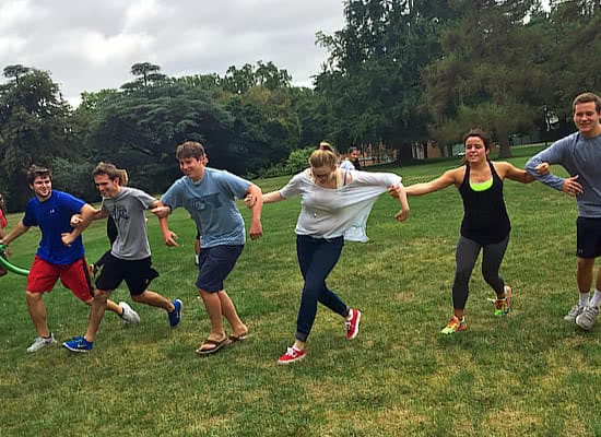 Several students running with arms linked in a grassy field