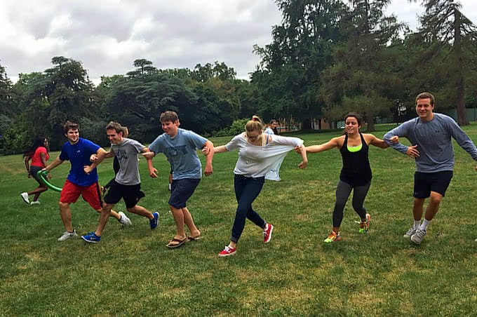 Several students running with arms linked in a grassy field