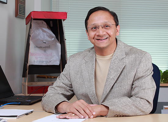 Gerard Athaide in his office, sitting at the desk.