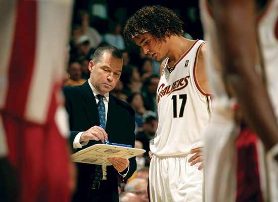 Malone speaks to a Cavalier player with his play board in hand, likely pointing to a game plan.