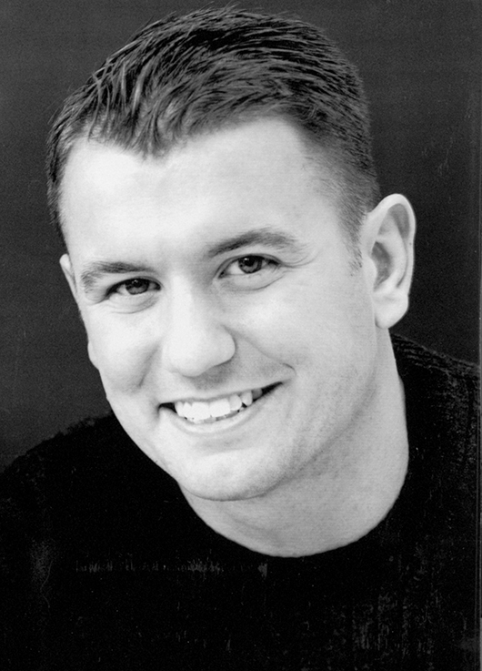 Black and white portrait photo of Sean smiling.