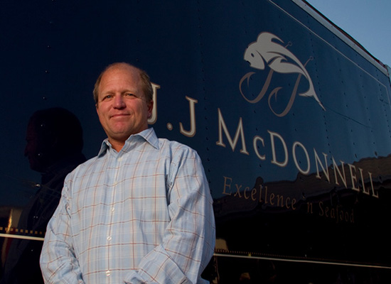 George McManus III standing by a JJ McDonnell truck, smiling.