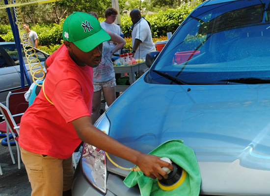 Young man polishes the hood of a car.