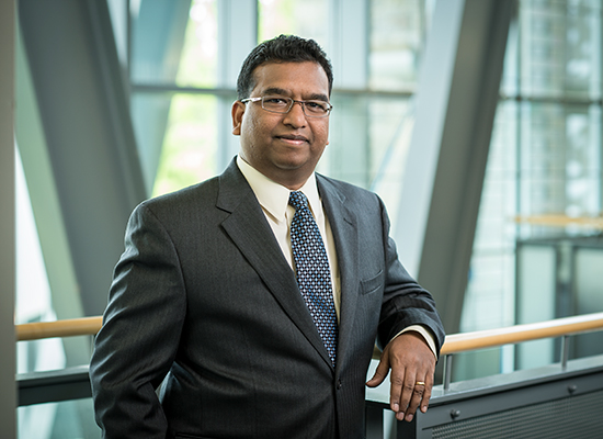 Frank D'Souza leans on railing inside the Sellinger School of Business.