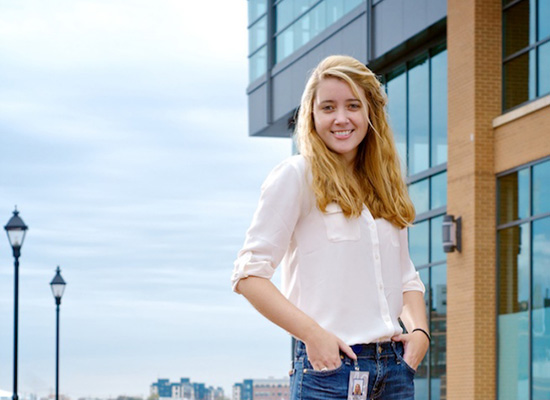 Portrait of Kasey standing outside near a glass building.