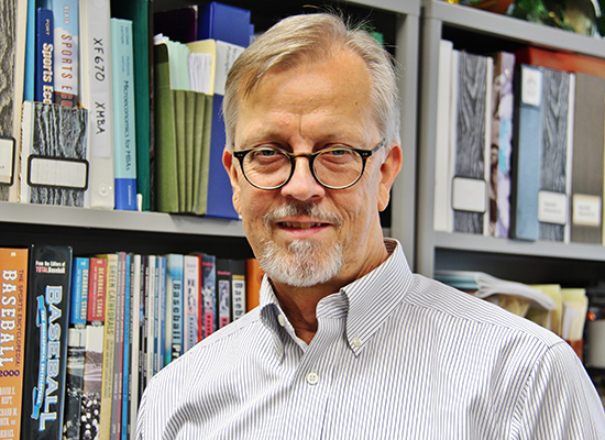 Photo of Steve Walters Ph.D., in office with bookshelves behind him.