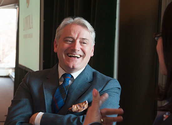 Graham McAleer crossing his arms and smiling as he speaks to event attendee.