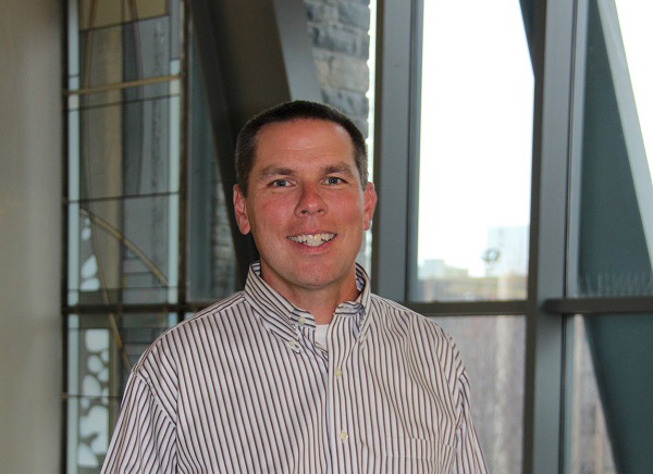 Rick Klink, Ph.D., smiles by the large windows of Sellinger's School of Business.