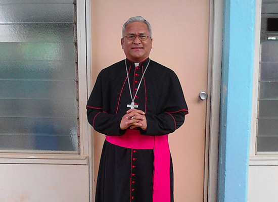 Cardinal Soane standing in his ecclesiastical black and cardinal red vestments.