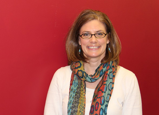 Beth Kotchick, Ph.D., smiles in photo with red background.