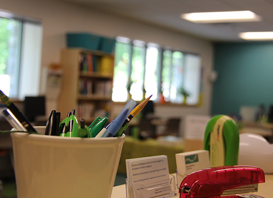 Pens, business cards, and stapler on the writing center's front desk.