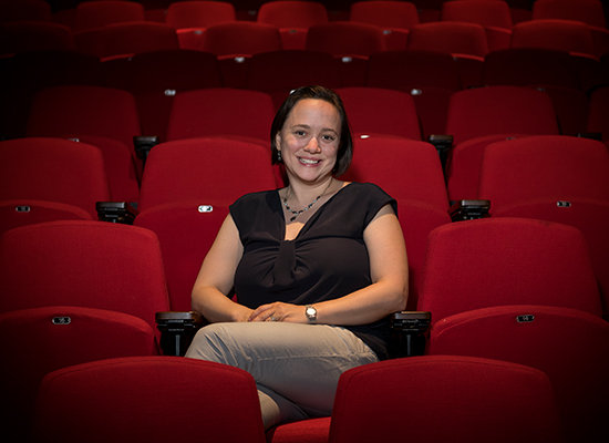 Natka sits among red theatre seats.