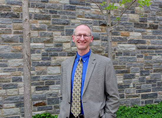 Picture of Kevin Hula standing by an alumni chapel wall.