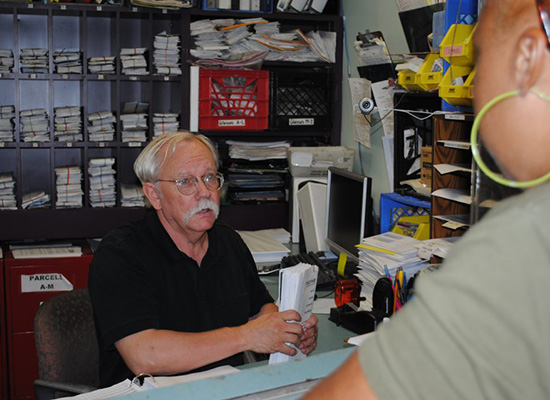 John Eckenrode behind a front desk, assisting someone.
