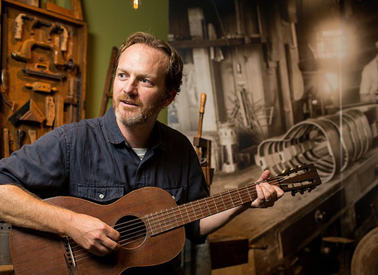 Chris Doyle sits with his guitar.