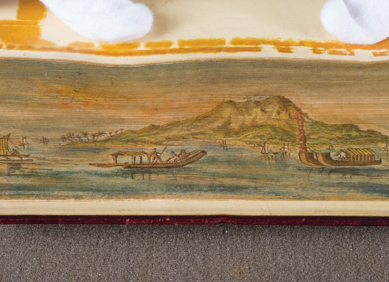 Fore-edge painting of boats on the water, surrounding a small, mountainous island.