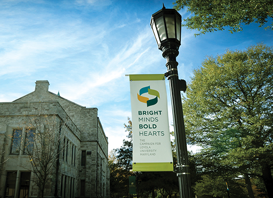 Street lamp on Loyola's quad with Beatty Hall, such trees, and blue sky above.