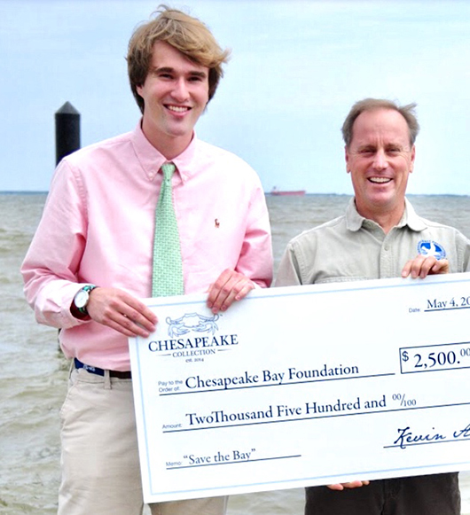 Matt stands by the water, holding a large check.