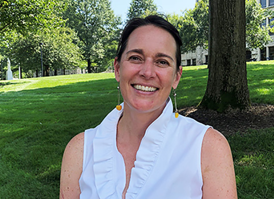 Wendy smiles with Loyola's sunny quad behind her.