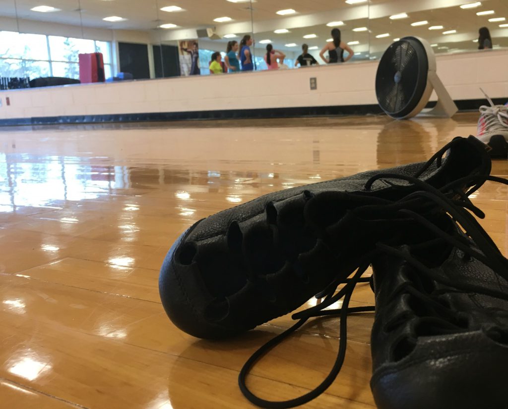 Black Irish dancing shoes on a wooden dance floor