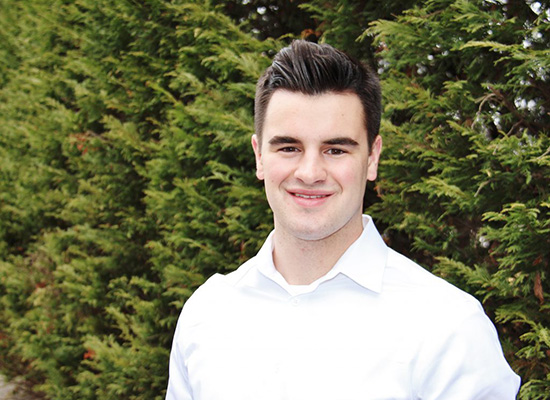 Portrait of Quinn Cosgrave in front of evergreen trees.