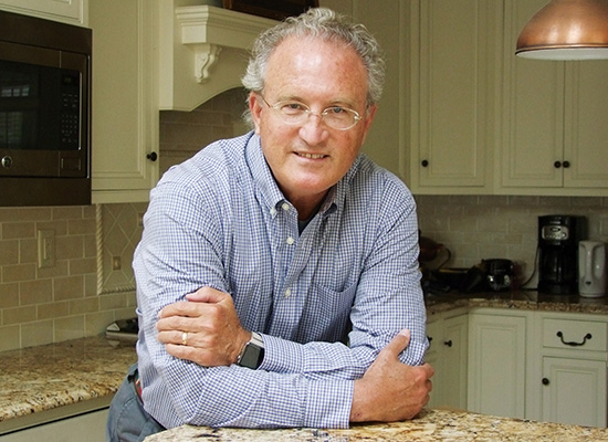 Photo of Mark Bowden leaning on kitchen counter with his arms crossed.