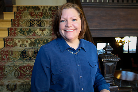 Lisa smiling in front of main staircase inside the humanities manor.