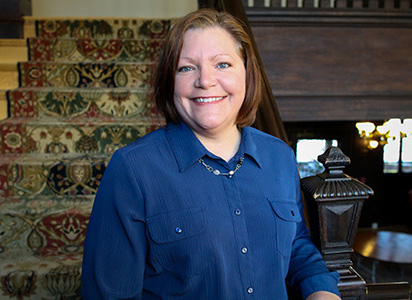 Lisa smiling in front of main staircase inside the humanities manor.