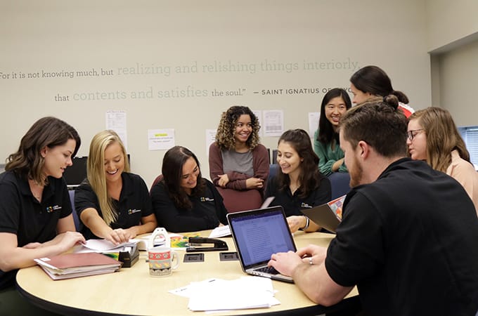 Group of Loyola Clinical Center assistants smiling and working at a table