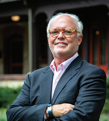 Jim Forbes stands with his arms crossed in front of humanities mansion.