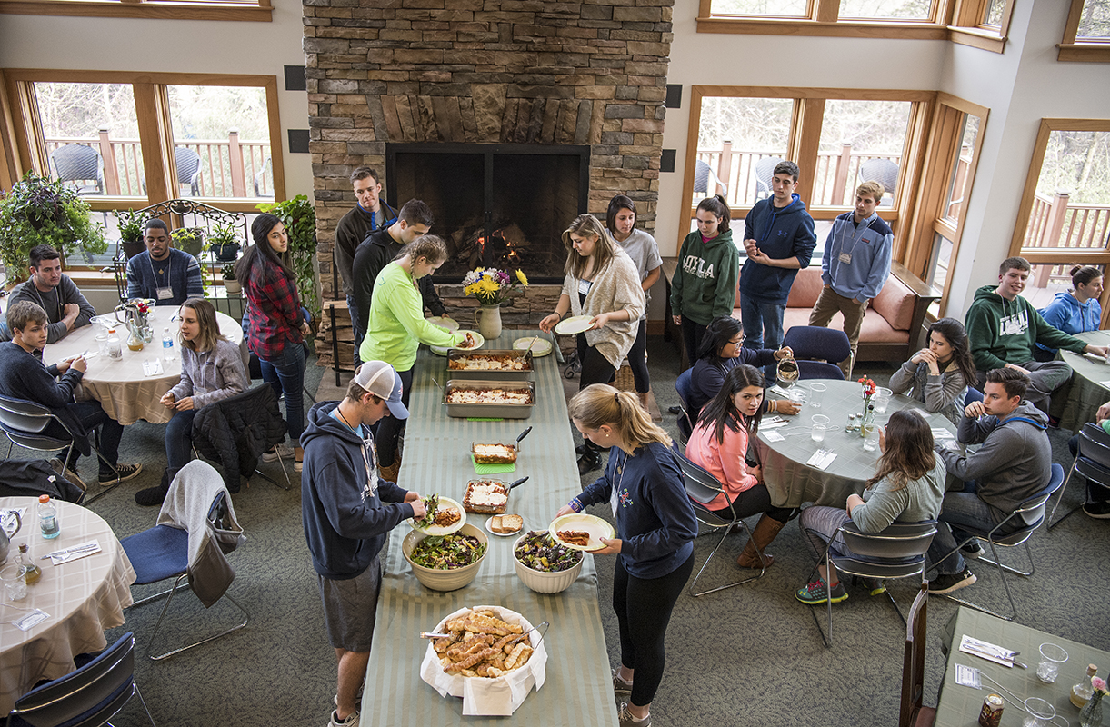 Students gather around their tables and make their plates with salad and lasagna.